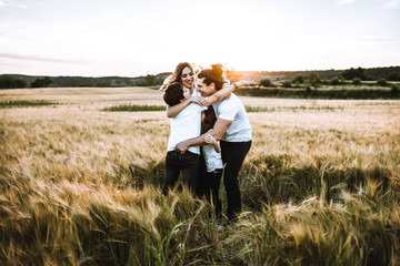 Happy family hugging in the field and smiling. Family in a sunset