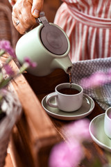 A woman pours tea into a mug of tea. Cozy atmosphere and homemade breakfast at home. Toned photo.