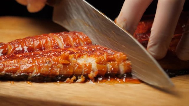 Chef cutting fried eel on the board.