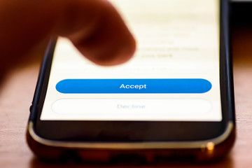 Accept button on smartphone screen closeup with human finger pointing to it