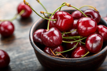 Fresh sweet cherries bowl with leaves  on a wooden table