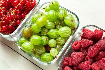 different summer berries red currant, gooseberry, raspberry in glass trays.