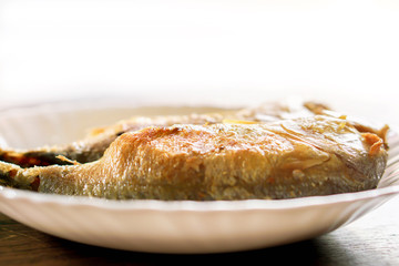 Closeup fried mackerels on white ceramic plate and wooden table with natural sun light background. Fried mackerels popular to eat in Thailand and eat with Thai shrimp paste chili sauce(Nam Phrik Kapi)