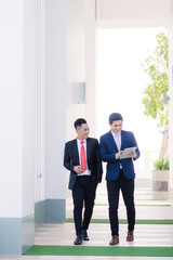 Two Vietnamese male coworkers talking and smiling