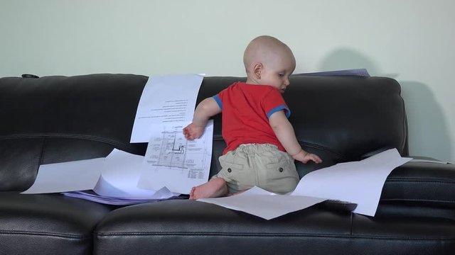 Caucasian child do mess with father documents papers on sofa at home