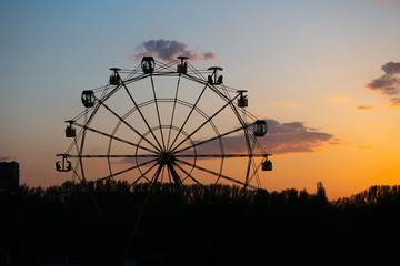 Silhouette of old soviet Ferris wheel against sunset sky