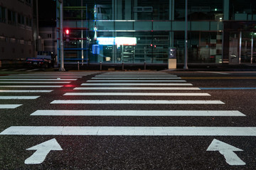 Pedestrian crossing with directional arrows at night. pedestrian marking on wet pavement. red...