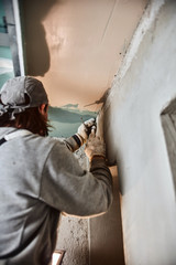 Construction worker plastering gypsum walls inside the house.