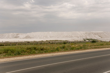 Big autumn field with trees far away and clouds in the blue sky. Asphalt road. Travelling