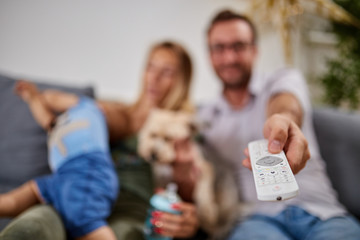Young parents watching TV with baby boy.