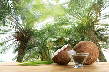 Coconut and natural organic oil on wooden table against tropical palm trees