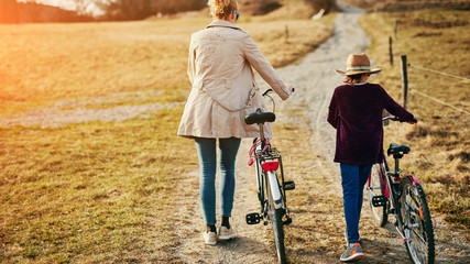 Naklejka premium Mother and daughter with bicycles on countryside.