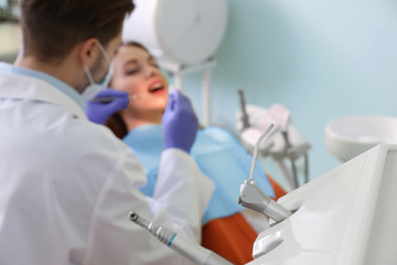 Naklejka na ściany i meble Closeup view of professional dentist's equipment and blurred doctor with patient on background. Space for text