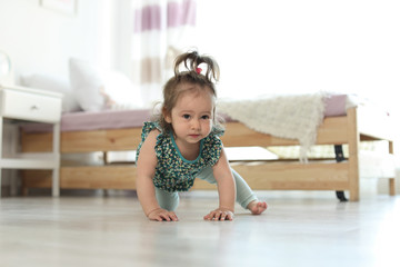Naklejka premium Adorable little baby girl crawling on floor in room