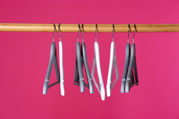 Wooden rack with clothes hangers on color background