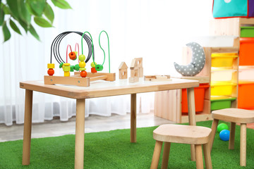 Stylish playroom interior with toys and modern wooden furniture