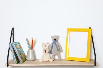 Composition with soft toys and photo frame on shelf. Child room interior decor
