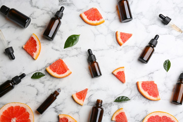 Fototapeta na wymiar Flat lay composition with grapefruit slices and bottles of essential oil on marble background