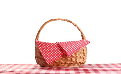 Empty picnic basket on checkered tablecloth against white background