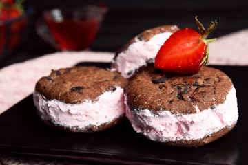 Sweet delicious ice cream cookie sandwiches with strawberry on plate, closeup