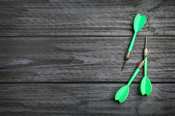 Dart arrows on wooden background, flat lay. Space for text