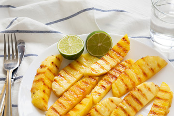 Grilled pineapple slices with lime on a white plate, low angle view. Close-up.