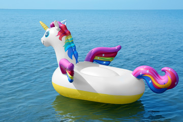 Funny inflatable unicorn ring floating on sea water. Summer vacation