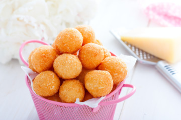 Homemade cheese balls in a pink basket on a white table, horizontal