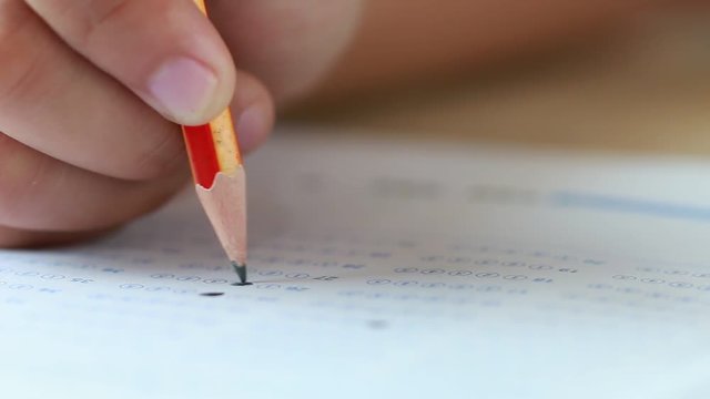 Student hand testing doing test exam with pencil drawing selected choices on answer sheet in school final exams at college or university. Taking multiple choice for assessment in examination classroom