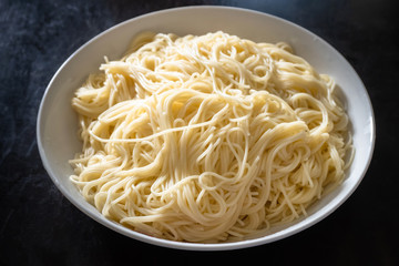 plate of plain spaghetti on dark wooden table