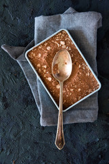 Old metal spoon with cocoa powder and oats, dark blue background.
