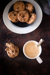 Cookies with chocolate and hazelnuts, perfect for coffee or tea in the afternoon. Brown board and dark background
