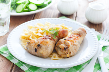 Chicken legs stuffed with champignons on a white plate with pasta, horizontal