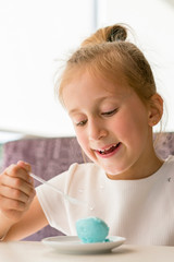 Little girl eating ice cream in a cafe. Adorable little girl eating ice cream at summer. close up. vertical photo