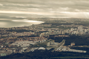 Fototapeta na wymiar Portuguese capital Lisbon from above. City skyline with clouds in the sky. Buildings and mouth of the river name Tejo with landscape and ships on the horizon
