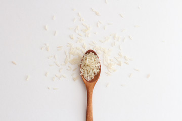 Fototapeta na wymiar rice grains on a wooden spoon on a white background