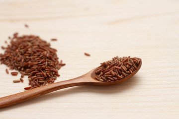 wild brown ruby rice in a wooden spoon on wooden board
