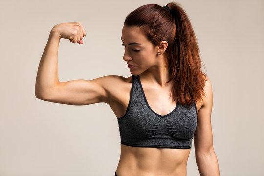 Strong woman flexing her bicep and showing strength in a studio