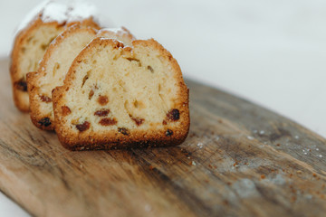 Raisin cake, dusted with icing sugar. Cupcake with raisins on a wooden board
