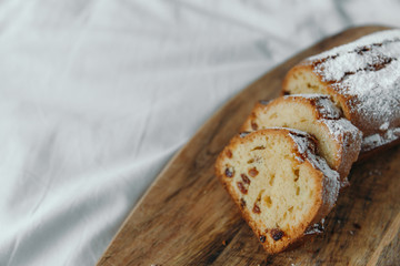 Raisin cake, dusted with icing sugar. Cupcake with raisins on a wooden board
