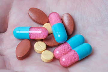 Capsule and pills medicines in hand with pink background