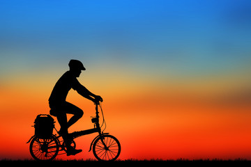 Naklejka na ściany i meble Silhouette man and bike relaxing on blurry sunrise sky background.