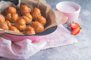 Freshly baked profiteroles only from the oven prepared for coating with pink icing.