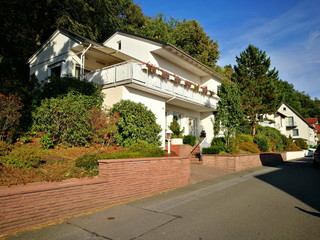 Große weiße Villa mit Balkon im Grünen vor blauem Himmel im Sonnenschein in Oerlinghausen bei...