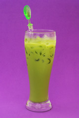 Green milk tea in glass on purple background