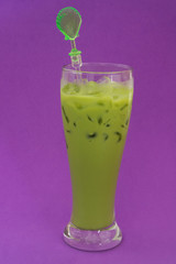 Green milk tea in glass on purple background
