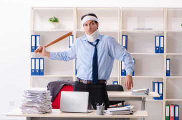 Young injured male employee working in the office 