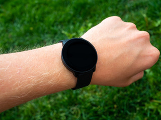 Hand with smart watch against green grass