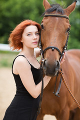 Portrait of young pretty cheerful woman with horse at summer 