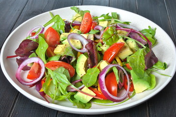 Avocado salad with shrimps, cherry tomatoes, arugula beet leaves, red onion, yellow sweet pepper. Healthy lunch plate with vegetables and shrimps